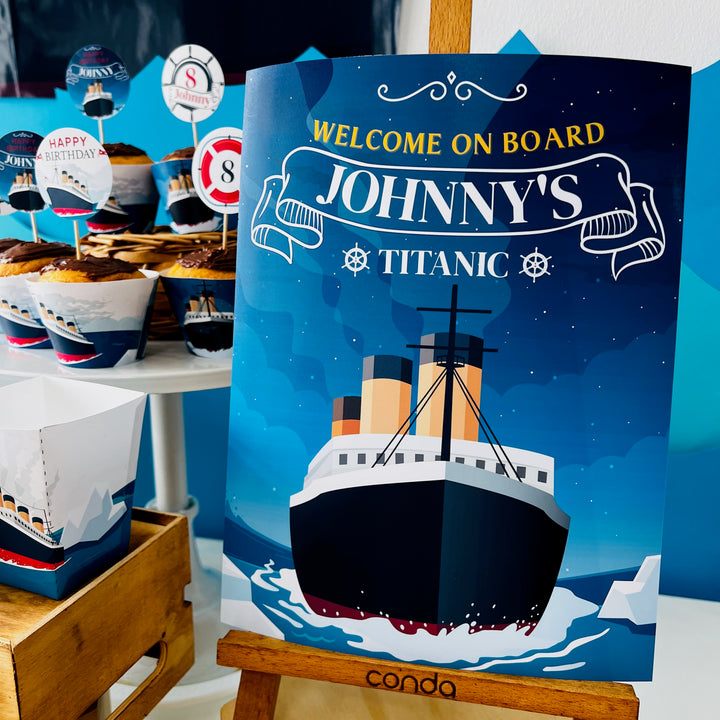 Decorative sign for a Titanic-themed party with cupcakes and cake stands in the background.