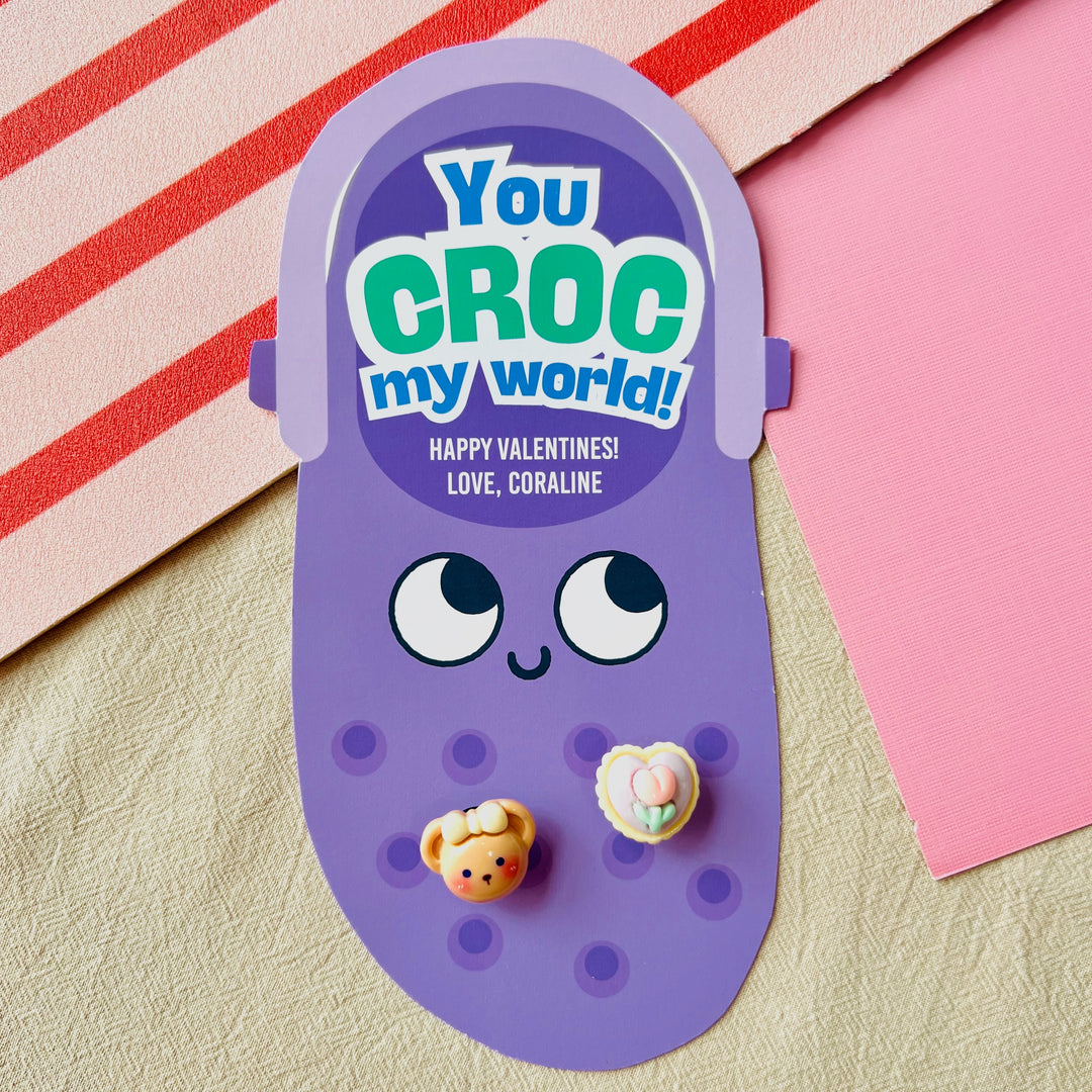 Printable Crocs Jibbitz holder Valentine card in purple with "You Croc My World!" pun and attached bear charm for classroom gifts
