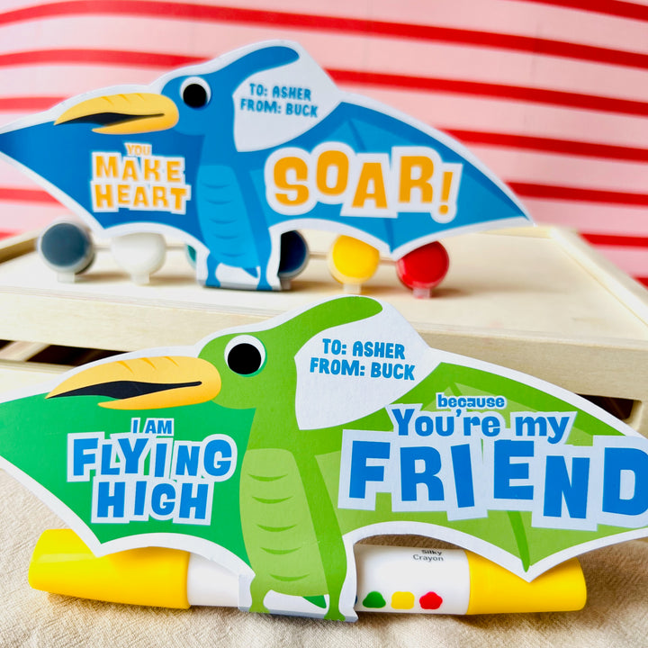 Close-up of printable pterodactyl card holding small gifts with "I Am Flying High" pun for boys' valentines day gifting